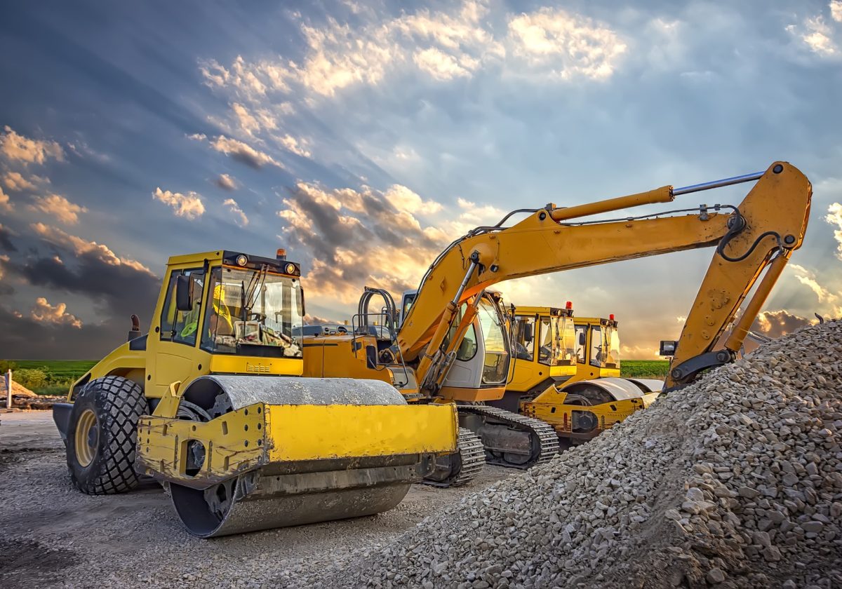 Parked drum roller and excavators at the construction site, after work